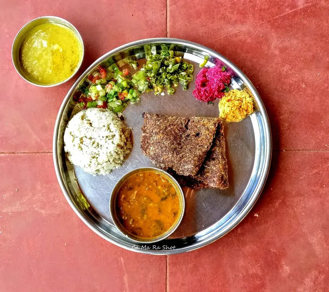 A thali of ragi rotis with sides — sambar, chutney, beetroot, salsa, and rice